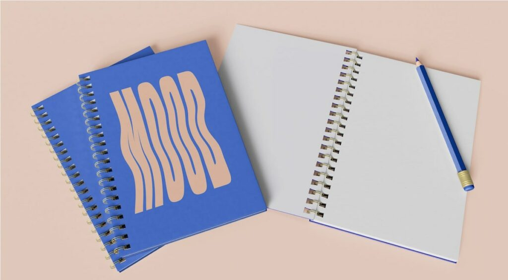 A purple ring-bound notebook titled, Mood next to an open page and pencil.