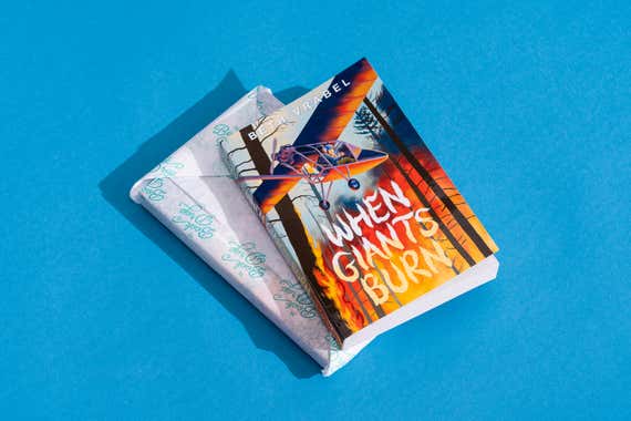 A book called When Giants Burn resting on top of a book wrapped in tissue paper.