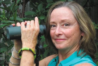 Portrait of Trish O'Kane, holding up her binoculars