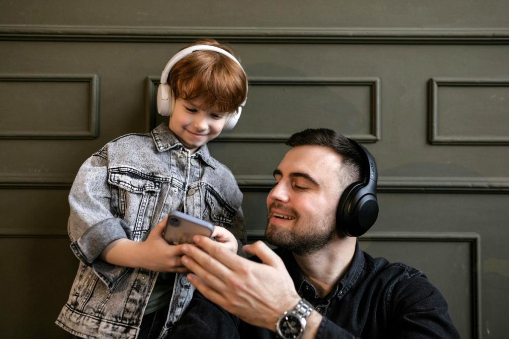 A father and son listen to something on the phone. 