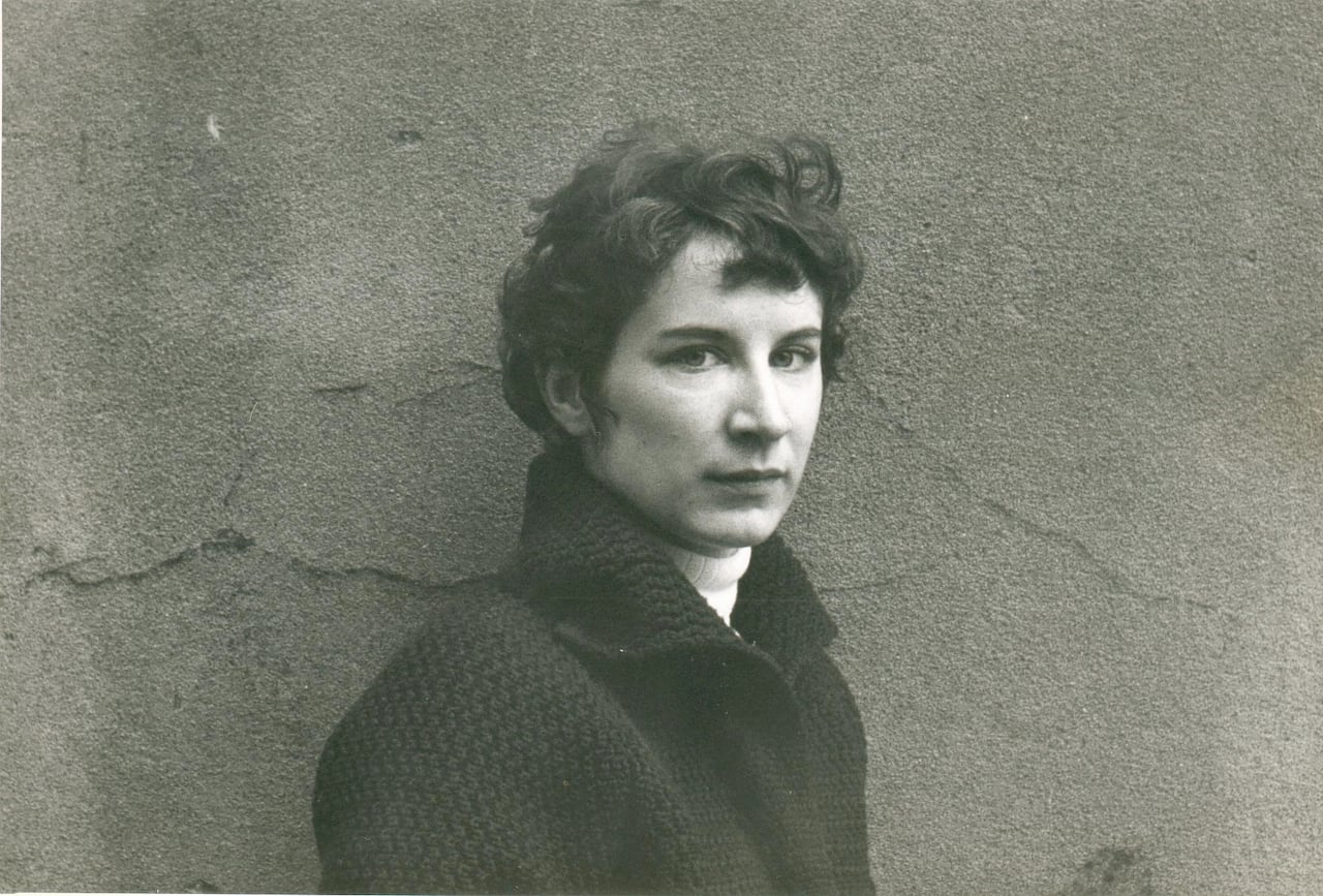 A woman stands against a wall for a photo